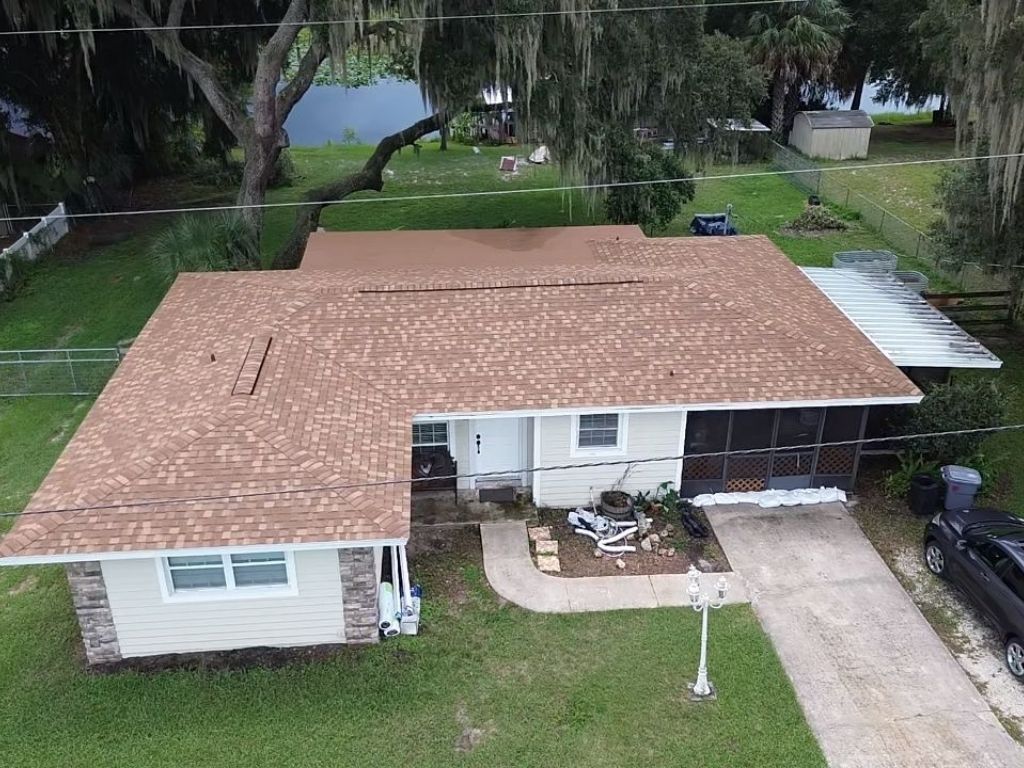 user-inserted Aerial view of a residential Florida home with asphalt shingle roof after roof repair or inspection.