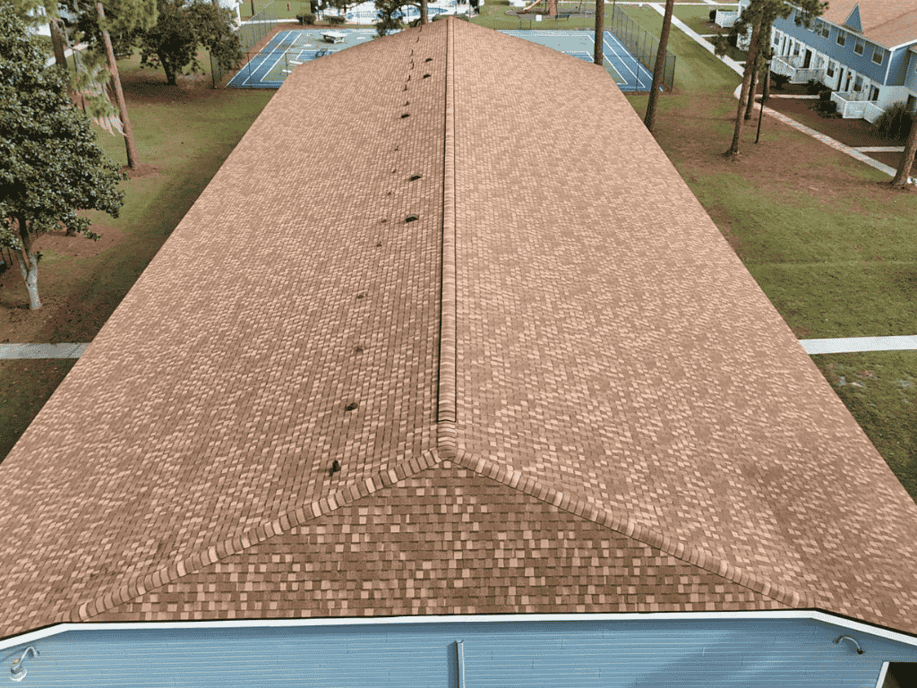 user-inserted Aerial view of a well-maintained roof showing shingle patterns and roofing details. The image showcases the entire length of the roof with no visible damage, surrounded by greenery and tennis courts.