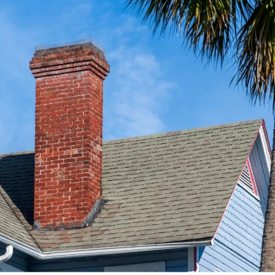 Florida Hurricane Season Has Started — Here's How to Know If Your Roof Is Truly Ready 2 Close-up of an aging asphalt shingle roof on a Florida home with a brick chimney and palm tree, showing weathered shingles that may need inspection before hurricane season.