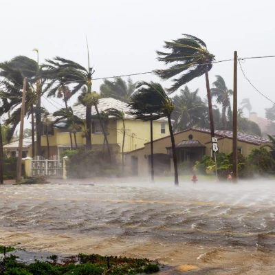 Florida Hurricane Season Has Started — Here's How to Know If Your Roof Is Truly Ready 1 Severe hurricane flooding overtaking a Florida street with palm trees bent by high winds and residential rooftops visible in the background.